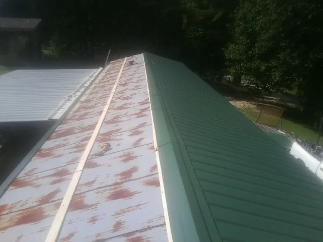 Old rusted panels beside newly installed green metal roofing — Wind Damage Roof Repair by Roofing Brothers in Parma