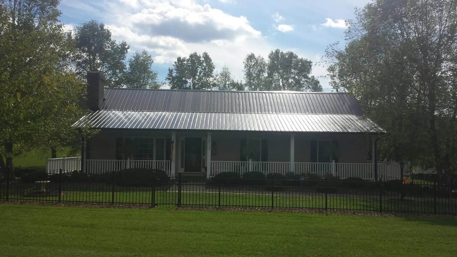 Gray metal roof on a brick ranch with a full width front porch — Gutter Guard Installation work by our crew in Parma